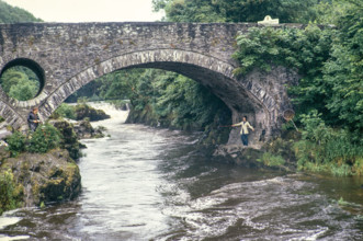 Woman fishing standing under bridge.