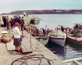 People boarding tour boats from the quayside in the harbour at Hugh Town.