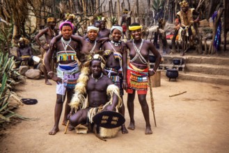 A group of Zulu people in traditional attire at a cultural village in South Africa.