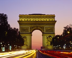 FRANCE, Ile de France, Paris, Arc de Triomphe at night with light trails from passing cars.