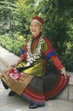 CHINA, Guizhou, Kiali, Seated Miao girl  wearing festival dress