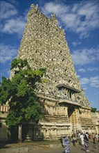 INDIA, Tamil Nadu, Madurai, Sri Meenakshi Temple pyramidal tower or gopuram with people walking