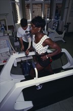 10001288 SPORT Athletics Health VO2 MAX Endurance Testing. Female athlete wearing breathing equipment and running on a treadmill with coach at her side