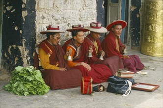 TIBET, Lhasa, Four monks seated and chanting in the street