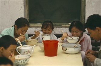 CHINA, Food, Eating, Family eating noodles at a table in the street
