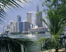 SINGAPORE, Singapore City, City skyscrapers and waterfront seen through palm leaves wth a white