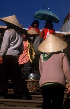 VIETNAM, Dalat, Women at Dalat market with wide straw hats and umbrella.