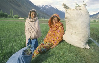 PAKISTAN, North West Frontier Province, Phandra, Ismaili girls sitting in fields with sacks.