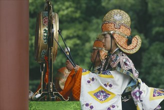 JAPAN, Honshu, Religion, Man in costume beating gong at festival