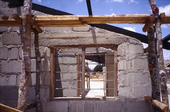 TANZANIA, Construction, Building site with unfinished block built house and barred window.