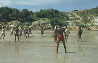 BRAZIL, Near Recife, Men playing football on the wet sand of the beach with sticks for goalposts