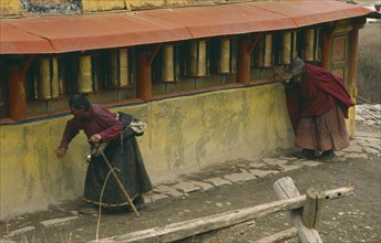 CHINA, Sichuan, Zoige, Tibetan pilgrims turning prayer wheels.