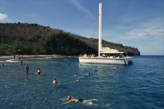 WEST INDIES, St Lucia, Transport, Catamaran tour.  Tourists swimming from moored boat with beach