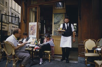 FRANCE, Ile de France, Paris,  A waiter carrying a tray with drinks to customers sat outside la