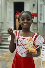 WEST INDIES, Barbados, Easy Hall, Young smiling girl in red and white dress with red ribbons in