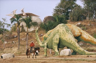 CUBA, Santiago De Cuba, Buccanao, Parco Prehistorico dinosaur replicas with man on horseback riding