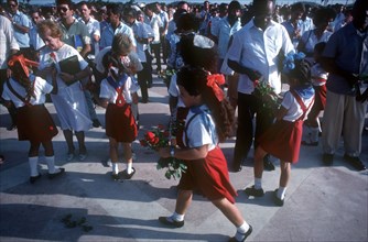 CUBA, Santa Clara, School children wearing red and white uniforms distributing red roses to adults