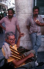 CUBA, Havana, "Three men on a street corner, one in a wheelchair smoking"