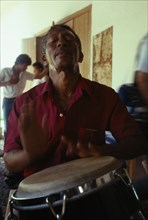 CUBA, Sancti Spiritus, Trinidad, Man playing tall bongo type drum with his hands