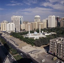 UAE, Abu Dhabi, Elevated view over mosque surrounded by trees and  high rise buildings near a road