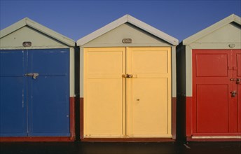 ENGLAND, East Sussex, Hove, Row of three brightly painted beach huts