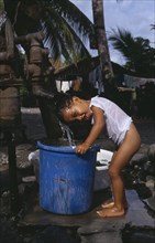 PHILIPPINES, Mindoro, Roxas, Young boy taking shower under water pump .