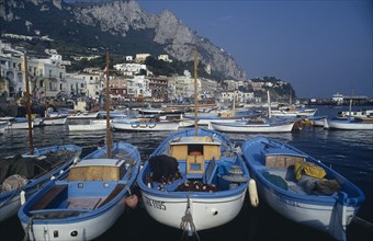 ITALY, Campania, Capri, Marina Grande. Moored boats on water with waterside buildings overlooked by