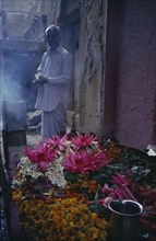 INDIA, Uttar Pradesh, Varanasi, Man standing by display of flowers and burning incense