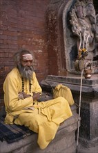 NEPAL, Kathmandu , Patan, Sadhu / Holy Man sitting by a statue of Ganesh