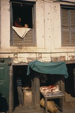 NEPAL, Kathmandu, Durbar Square butchers with display of goods and people at a window above