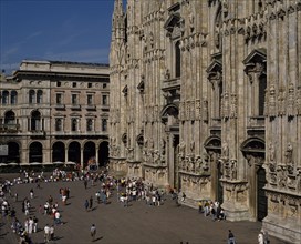 ITALY, Lombardy, Milan, Milan Cathedral exterior. Visitors on ground near front entrances