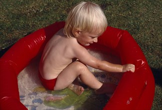 10017227 CHILDREN Leisure Swimming Young child playing in red padling pool