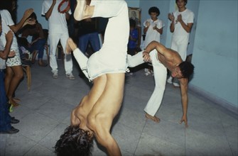 10018333 BRAZIL Amazonas Capoeira Local men in animated poses of martial arts  inside a small room with spectators.