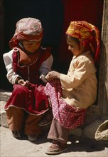 CHINA, Xinjiang Province, Children, Two Tadjik girls sitting on step beside wooden door frame.