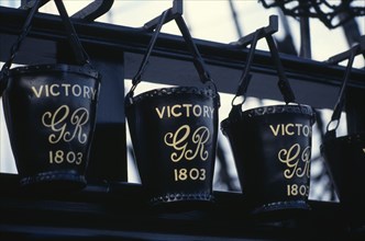 ENGLAND, Hampshire, Portsmouth, HMS Victory.  Detail of black leather buckets hanging from row of