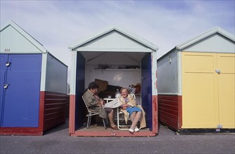 ENGLAND, East Sussex, Hove, Two elderly women sitting inside a beach hut on the seafront