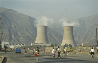 CHINA, Gansu Province, Lanzhou, Coal Power Station with people walking in the foreground.