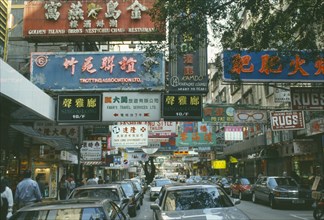 HONG KONG, Kowloon, Markets, Busy downtown street with traffic and overhanging shop signs.