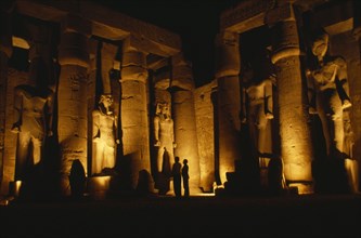 EGYPT, Luxor, The Temple illuminated at night with giant standing Statues of Rameses II