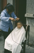 CHINA, Guanzhou, Barber cutting young boys hair