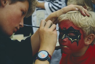 CHILDREN, Play, Face Painting, Young boy having his face painted with bat design.