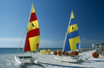 USA, Florida  , St.Petersburg, "Hobbie Cats with bright blue, red and yellow sails pulled up onto