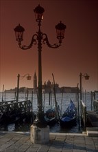 ITALY, Veneto, Venice, San Giorgio island behind moored gongolas and an ornate lampost
