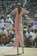 WEST INDIES, Barbados, Crop Over, Stiltman in pink and white at traditional harvest festival to