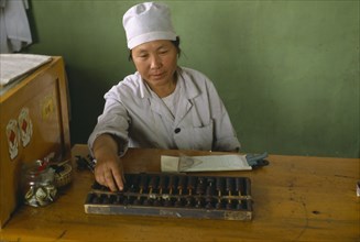 CHINA, Xinjiang, Turfan, Woman using Abacus