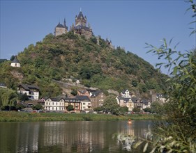 GERMANY, Rhineland, Cochem, Hilltop castle with conical towers overlooking houses beside the Mosel
