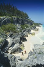 BERMUDA, Astwood Park, Couple walking on beach towards rocky cliffs