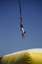 SPORT, Bungee Jumping, Jumper dangling above large inflatable.