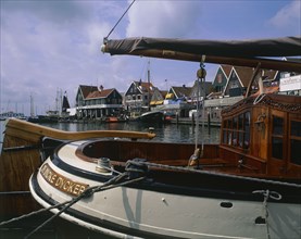 HOLLAND, North, Volendam, Harbour and buildings with many boats moored seen across the stern of a