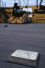 ENGLAND, Hampshire, Portsmouth, HMS Victory.  Detail of deck with cannon and brass plaque marking
